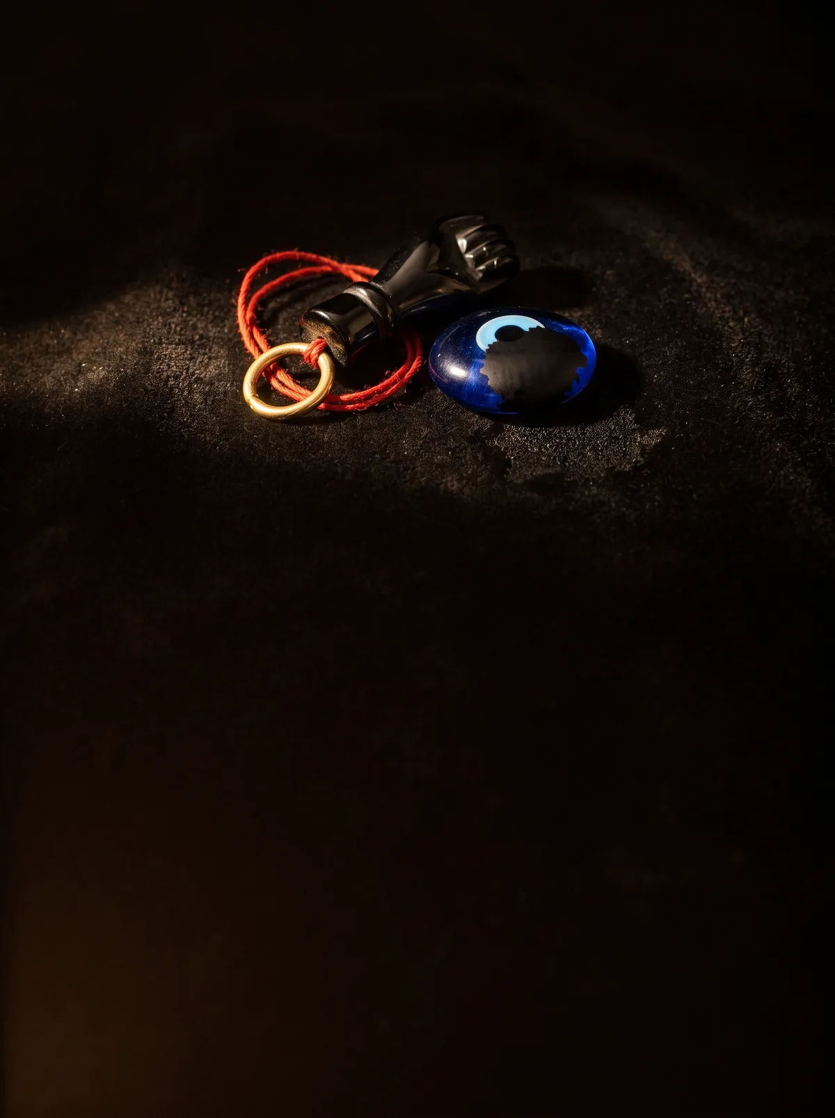Imagen generada con IA: amuleto de azabache con hilo rojo y una cuenta azul en forma de ojo